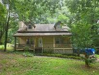 Charming two-story home with a covered front porch, landscaped yard, and mature trees providing shade at 33 Powder Dr, Dallas, GA 30157