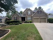 Charming brick home featuring a well-manicured lawn and a two-car garage at 223 Sterling Brook Ln, Canton, GA 30114