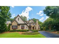 Charming stone and siding home with lush landscaping and a circular driveway at 145 Ardsley Ln, Alpharetta, GA 30005