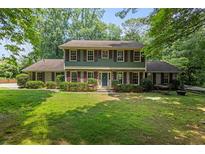 Charming two-story home with manicured lawn, green siding, red shutters and hammock at 3120 Beechwood Se Dr, Marietta, GA 30067