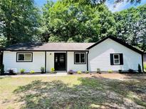 Charming home featuring a bright white exterior, black trim, complemented by a well-manicured front yard with lush landscaping at 373 Hemlock Dr, Lawrenceville, GA 30046