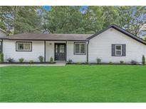 Charming single-story home with a lush green lawn, white siding, black trim, and neatly manicured landscaping at 373 Hemlock Dr, Lawrenceville, GA 30046