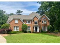 Beautiful brick two-story home with mature landscaping, a manicured lawn, and classic architectural details at 1813 Baldwin Farms Dr, Marietta, GA 30068