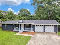 Charming single-story home with a welcoming front porch and a two-car garage, nestled in a lush, green landscape at 4720 Hull Rd, Conyers, GA 30094