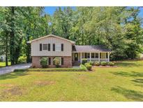 Charming two-story home boasts a welcoming front porch and a well-manicured lawn surrounded by mature trees at 3357 Huntwood Ct, Decatur, GA 30034