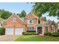 Beautiful brick home featuring a two-car garage, manicured lawn, and lush landscaping at 335 Scarborough Way, Alpharetta, GA 30022