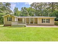 Charming ranch-style home with a welcoming front porch, lush green lawn and mature trees at 3440 Wilson Rd, South Fulton, GA 30349