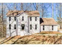 Charming two-story home with a white stucco exterior, a brown roof, and mature trees at 5050 Brownwood Dr, Powder Springs, GA 30127