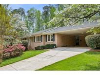 Charming brick home featuring a covered driveway and lush landscaping with flowering trees and shrubs at 3755 Kayanne Ct, Tucker, GA 30084