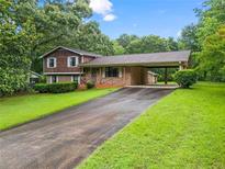 Charming home with a brick facade, wood siding, covered parking, and a spacious front yard at 140 Carriage Cir, Stockbridge, GA 30281