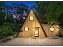 A-frame home featuring natural wood siding, black trim, unique round windows and stylish front door at 3620 Beaver Cove Rd, Cumming, GA 30041