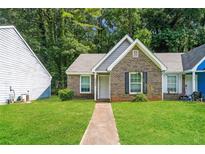 Charming brick home with a manicured lawn and inviting front entrance surrounded by mature trees at 5354 Cherry Wood Drive Dr, Stone Mountain, GA 30083