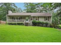 Charming one-story home featuring a covered front porch, light green siding, and a well-manicured lawn at 1952 Winding Creek Sw Ln, Marietta, GA 30064
