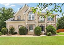 Charming two-story home with manicured lawn and decorative shrubs in a suburban neighborhood with blue skies at 2851 Weatherstone Se Cir, Conyers, GA 30094