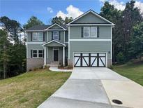 Charming two-story home with green siding, a two-car garage and well manicured landscaping at 66 Pine Creek Ct, Dallas, GA 30157