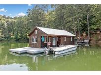Cozy lake house featuring a dock, metal roof, and wooded surroundings offering a serene waterfront retreat at 451 Wilderness Camp Rd, White, GA 30184