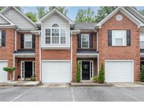 Brick townhome featuring a garage and black window shutters at 215 Morris Ln, Woodstock, GA 30188