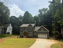 Two-story home with a well-manicured lawn and large driveway leading to an attached two-car garage at 4110 Post Gate Ct, Cumming, GA 30040