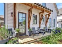 Inviting front porch with seating, brick flooring, and craftsman-style wood beam architectural design creates a welcoming outdoor space at 150 Ray Way, Chattahoochee Hills, GA 30268