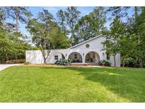 Stunning white home featuring arched front porch, lush lawn, and blooming hydrangea bushes at 5714 Braddock Ct, Atlanta, GA 30350