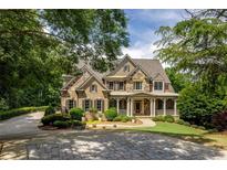 Stately brick and stone home boasts lush landscaping, circular driveway, and covered front porch at 930 Shepards Ct, Roswell, GA 30075