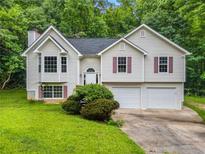 Charming two-story home featuring a well-maintained lawn and a two-car garage, nestled amongst mature trees at 87 Fair Havens Dr, Hiram, GA 30141
