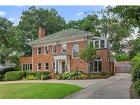 Stunning two-story brick home featuring a lush front yard, manicured hedges, and a brick chimney at 1036 Oxford Ne Rd, Atlanta, GA 30306