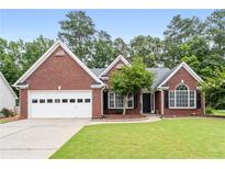 Charming brick home with a well-manicured lawn, attached garage, and inviting front entrance at 192 Sandhurst Ct, Suwanee, GA 30024