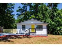 Charming home featuring a bright yellow door and freshly painted white brick, surrounded by lush greenery at 4244 Lindsey Dr, Decatur, GA 30035