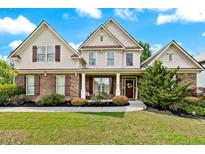 Charming two-story home boasts a manicured lawn, stone accents, symmetrical design, and a welcoming front porch at 1626 Waterchase Dr, Dacula, GA 30019