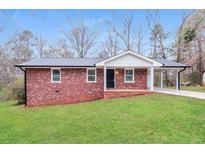 Charming brick home featuring a well-manicured lawn and covered parking area at 101 Longstreet Cir, Oxford, GA 30054