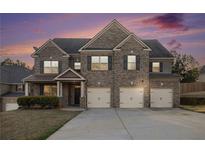 Charming two-story brick home featuring a three-car garage and meticulously manicured lawn at 7691 Brazos Trl, Fairburn, GA 30213