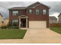 Two-story brick home boasts a well-manicured lawn and an attached two-car garage, providing ample space for parking at 11547 Hathaway Dr, Hampton, GA 30228