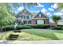 Beautiful two-story brick home with a manicured lawn and a welcoming front porch with beautiful bushes at 4770 Spring Park Cir, Suwanee, GA 30024