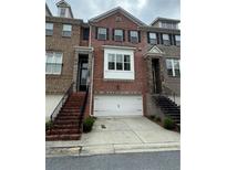 Brick townhome featuring a two-car garage, stairs to front door, and classic architectural details at 4172 Townsend Lane, Dunwoody, GA 30346