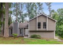 Charming two-story home with neutral siding, manicured lawn, and inviting curb appeal in a lush, wooded setting at 6249 Townsend Way, Riverdale, GA 30296