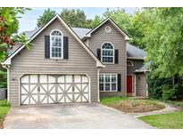Charming home featuring neutral siding, two-car garage, arched windows and a well-manicured lawn at 3554 Cherry Blossom Court, Loganville, GA 30052