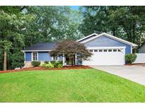 Charming blue home featuring a well-manicured lawn, landscaping, and a two-car garage at 195 Ansley Ct, Roswell, GA 30076
