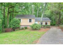 Inviting single-Gathering home featuring a quaint front yard and a long driveway surrounded by mature trees at 3812 Clare Ct, Duluth, GA 30096
