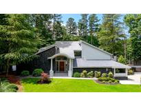 Striking exterior of a home with stone accents, gray siding, and a manicured lawn surrounded by mature trees at 4070 Whitewater Creek Rd, Atlanta, GA 30327