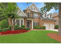 Charming two-story brick home with a well-manicured lawn, mature trees, and a two-car garage at 904 Urban Ash Ct, Johns Creek, GA 30022