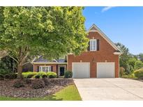 Charming two-story brick home with a well-maintained lawn, mature tree and a two-car garage at 13995 Mariners Cv, Alpharetta, GA 30005