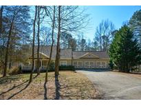 Traditional home showing attached three-car garage and covered porch with neutral siding and dark-stained trim at 6865 Cowan Mill Rd, Winston, GA 30187