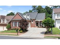 Charming brick home featuring a well-manicured lawn, mature trees, and a private driveway at 1560 Heritage Trl, Roswell, GA 30075