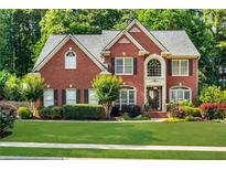 Charming brick home featuring lush landscaping, a manicured lawn, and a welcoming front entrance at 660 Briarleigh Way, Woodstock, GA 30189