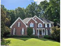 Charming two-story brick home with black shutters, white trim, lush landscaping, and a well-manicured lawn at 1620 Silverleaf Way, Alpharetta, GA 30005