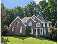 Beautiful two-story brick home featuring manicured lawn and mature trees at 1620 Silverleaf Way, Alpharetta, GA 30005