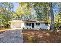 Charming home with a single-story layout, a covered parking area, and surrounded by mature trees at 409 Colette Ln, Social Circle, GA 30025