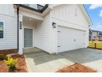 New construction shows a light gray front door and white garage door and siding with black iron hardware at 8502 Polston Lot 144 Pl, Douglasville, GA 30134