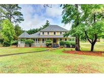 Charming yellow home with a welcoming porch, landscaped front yard, and mature trees creating a picturesque curb appeal at 5179 Beech Forest Sw Dr, Lilburn, GA 30047